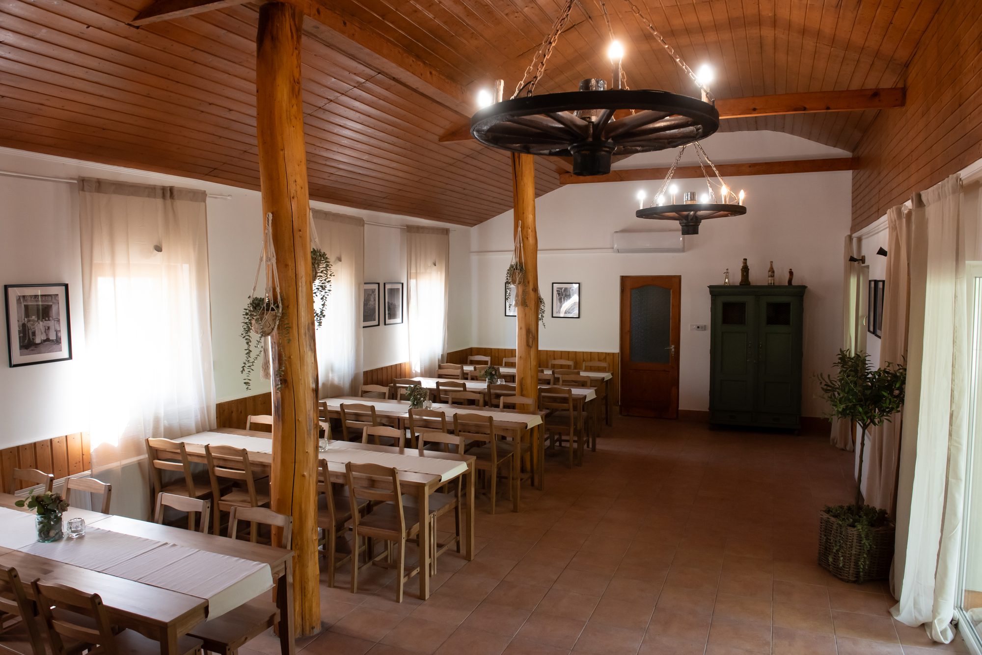 A rendezvényterem belső tere megterített asztalokkal, kovácsoltvas csillárokkal.